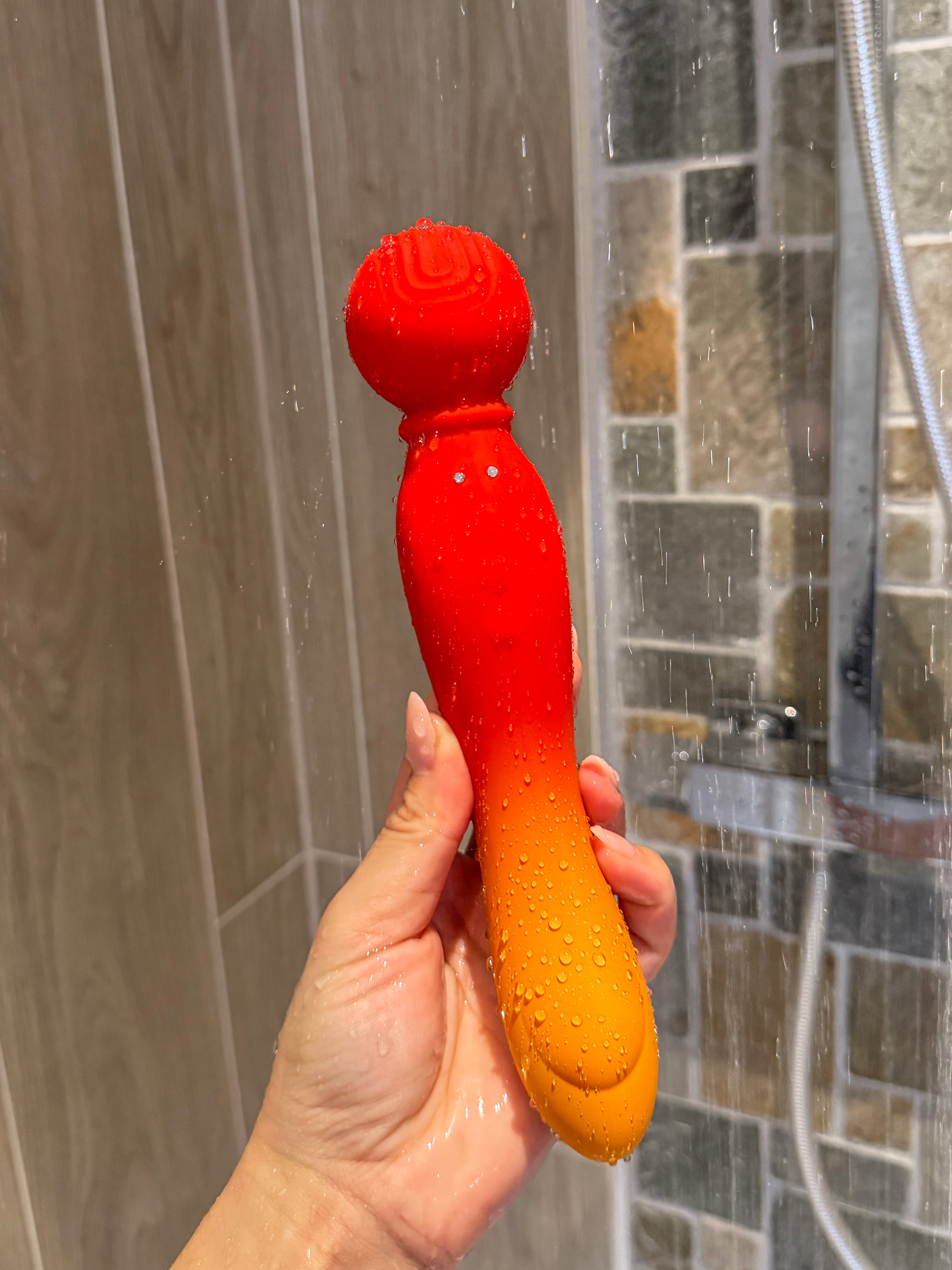 A vibrant red and orange gradient silicone vibrator with a textured, rounded head.