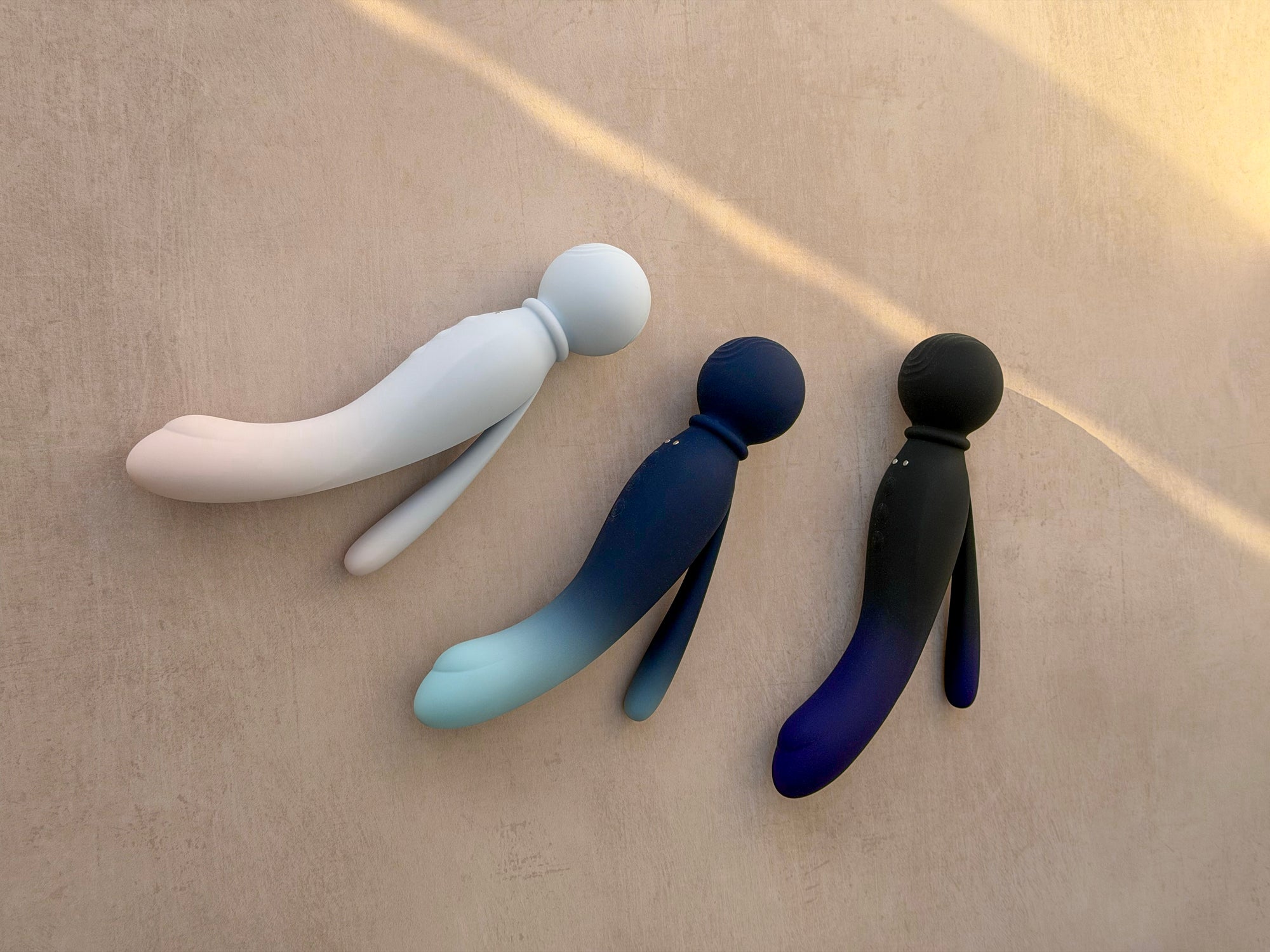 Three sleek, minimalist silicone body-shaped vibrators in white, blue gradient, and black gradient.