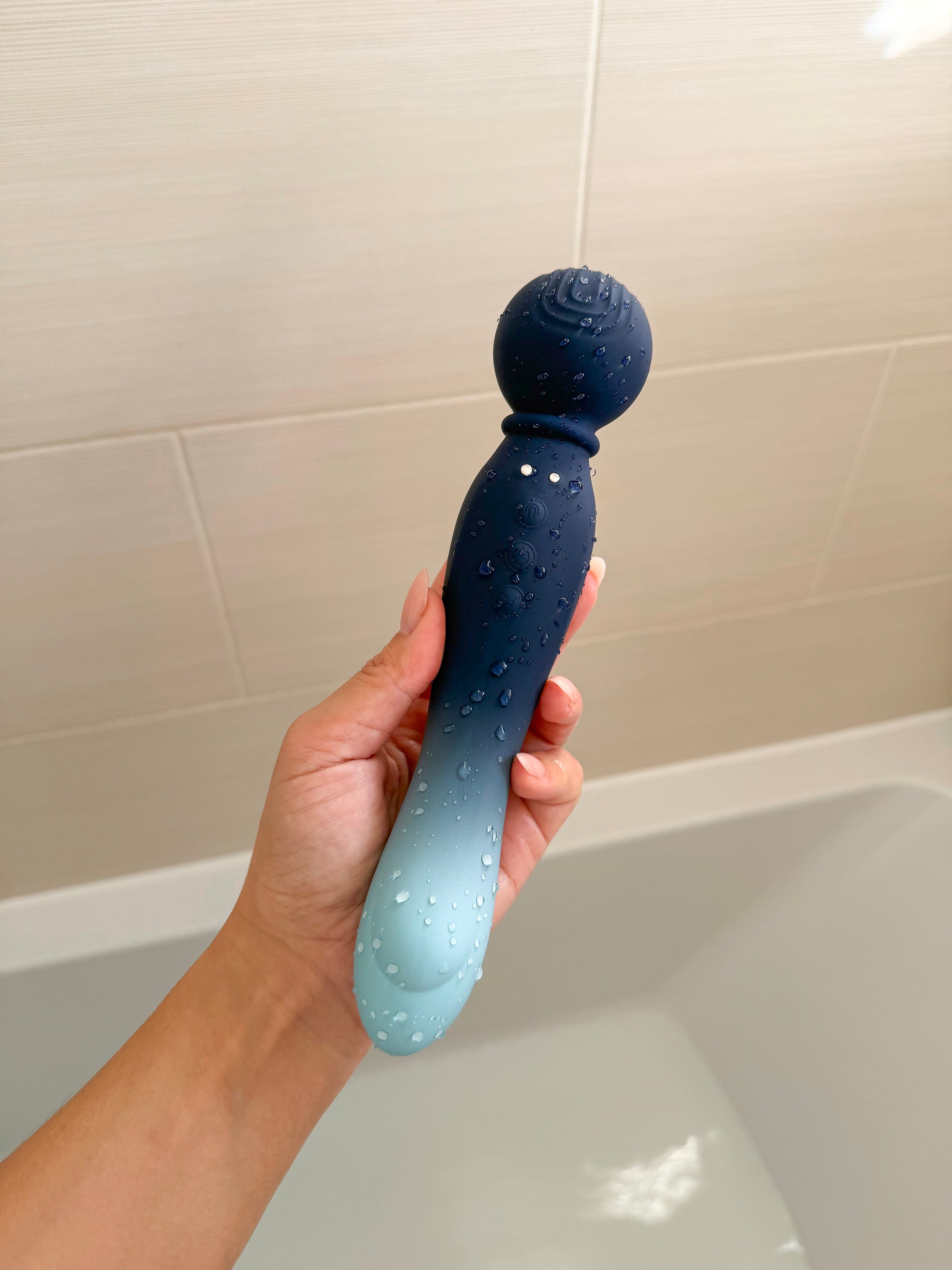A sleek, gradient blue silicone toy with a textured spherical head and subtle white dots along its body.