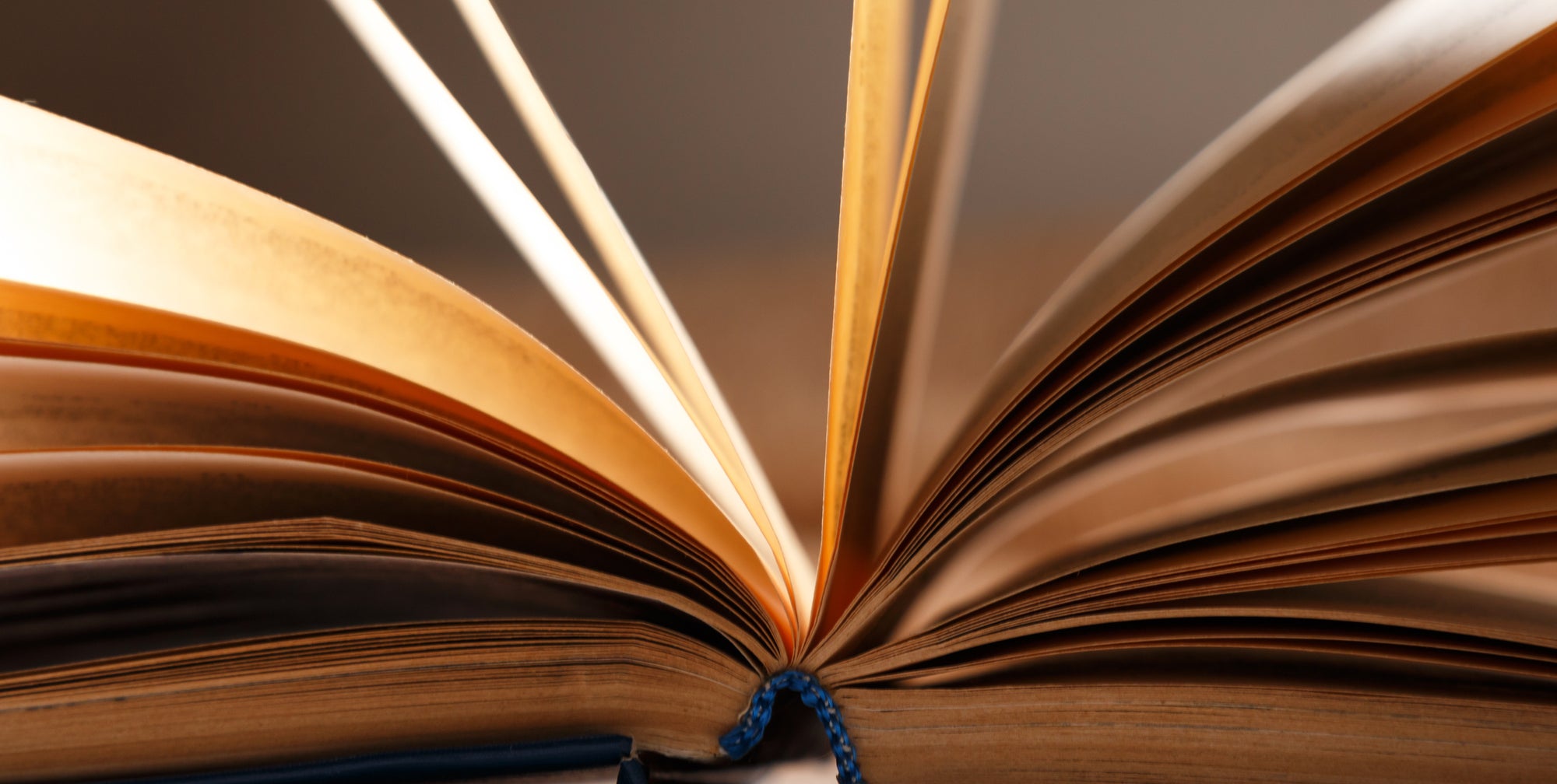 An open book with aged, yellowed pages and a blue braided bookmark.